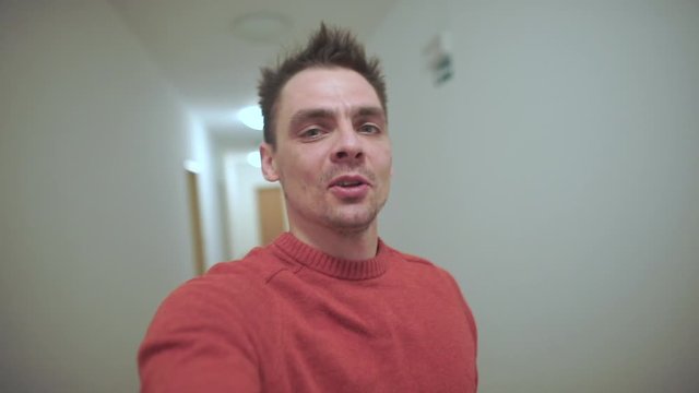 A guy takes a video of himself on the corridor of an apartment building.