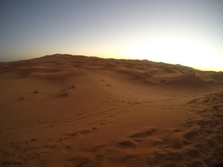 Fototapeta na wymiar The sun behind the dunes at dawn of the Merzouga desert in the Erg Chebbi Dunes. Morocco