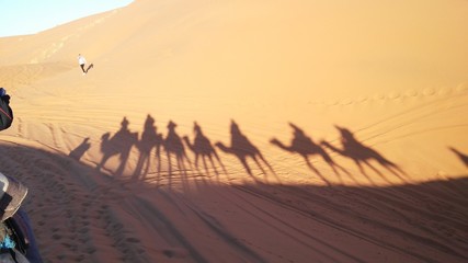 Fototapeta na wymiar Silhouettes On top of a dromedary in the Merzouga desert in the Erg Chebbi Dunes. Morocco