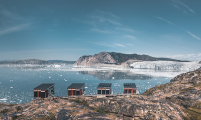 Panoramic image of Camp Eqi at Eqip Sermia Glacier in Greenland. nature landscape with lodge cabins. Midnight sun and pink sky. Tourist destination Eqi glacier in West Greenland AKA Ilulissat and © Mathias