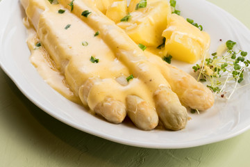 white asparagus poured with .hollandaise sauce, potatoes with chives and sprouts.