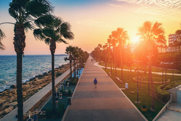 Limassol promenade or embankment at sunset. Aerial view of famous Cyprus alley with palms and walking people. Mediterranean resort in evening time, toned