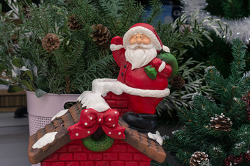 A fragment of a compositional Christmas toy under the Christmas tree, Santa Claus with gifts stands on the roof of the house. The toy symbolizes the New Year.