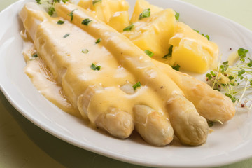 white asparagus poured with .hollandaise sauce, potatoes with chives and sprouts.