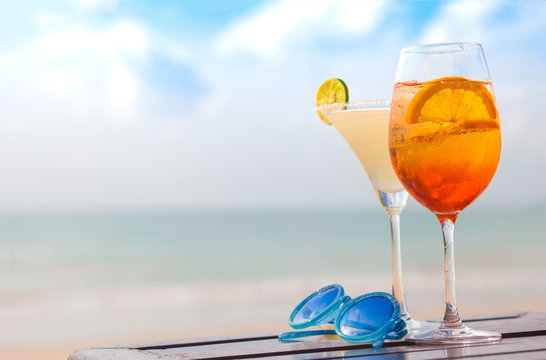 margarita cocktail and aperol spritz on table by the beach