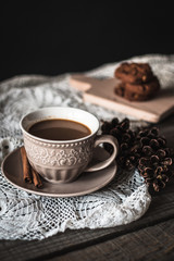 Hot coffee with cinnamon sticks and cookies on a wooden background