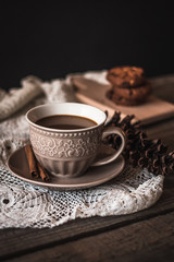 Hot coffee with cinnamon sticks and cookies on a wooden background