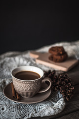 Hot coffee with cinnamon sticks and cookies on a wooden background