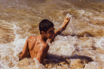 A young guy swims in the spray of the sea. He is laughs and scream..