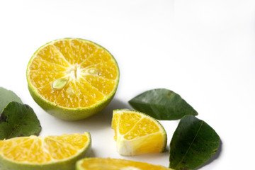 Group of fresh green citrus fruits and their leaves which have orange color inside and slice in different size and set in white color
