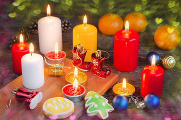 Burning candles with Christmas decorations and gingerbread on a wooden background. Selective focus