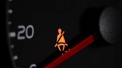 The yellow warning light flashes on the dashboard of the vehicle. Unfastened seat belt. Macro close up. - Powered by Adobe