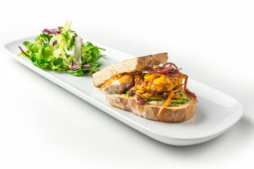 Breaded fish fillet sandwich with vegetables and mustard