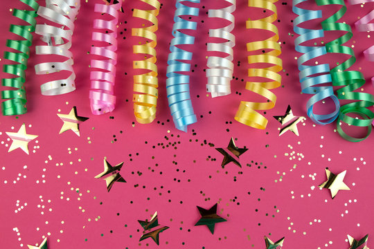 Carnaval festive curling colorful paper streamer decorations on pink background