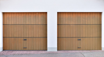 Two brown garage doors in a European city. Two garages