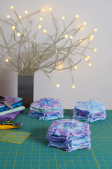 Stacks of hexagonal patchwork blocks, quilting accessories, table lamp on a cutting mat