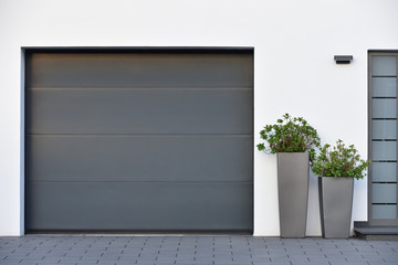 Modern gray garage, next to the Scandinavian-style house. Private garage with automatic door in a...