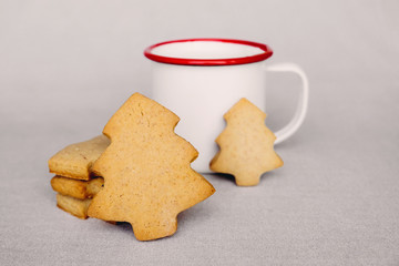 Stack of delicious freshly baked homemade cookies in the shape of Christmas tree and cup of hot drink. Holiday breakfast. Space for text. Snack for Santa or food for kids.
