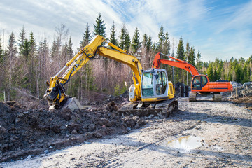 Yellow and orange excavator building a road deep in the forest. Rusko, Finland.