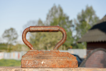 Old rusty Vintage iron with big corroded handle for ironing. Antique household item on sunny day