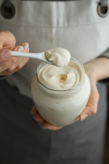 Sour cream in a glass jar with a spoon. 