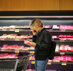 man purchasing a packet of meat at the supermarket