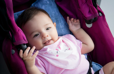 baby girl lying in a stroller, eating apron