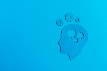 Brain works concept. Thinking, creativity concept of the human head with gears on blue background