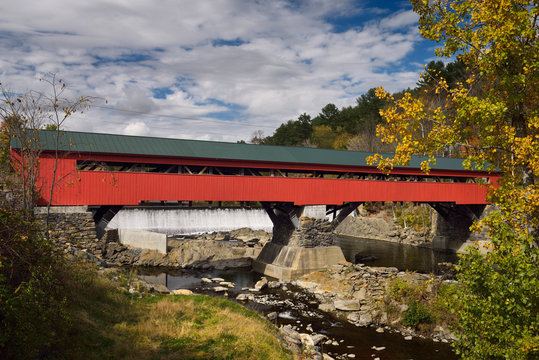 Hydro dam falls at red wooden covered bridge in Taftsville Vermont in the Fall