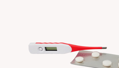 Digital thermometer and white fever pills isolated in white background