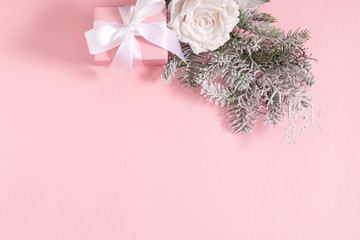 Christmas holiday composition. Gift box, fir tree branches, flowers on pastel pink background. Christmas, New Year, winter concept. Flat lay, top view, copy spac