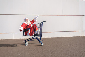 Supermarket cart with Santa Claus inside. Shopping for Christmas concept.