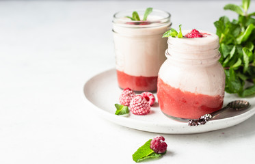 Healthy layered raspberry and yogurt smoothie or cocktail in mason jar with fresh berries and mint. Well being and weight loss concept. Natural detox.