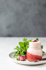 Healthy layered raspberry and yogurt smoothie or cocktail in mason jar with fresh berries and mint. Well being and weight loss concept. Natural detox.