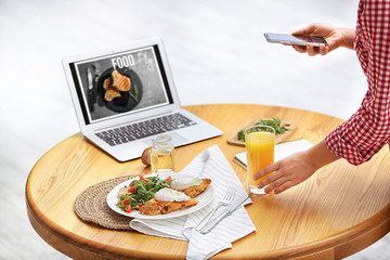 Food blogger taking photo of her lunch at wooden table indoors, closeup