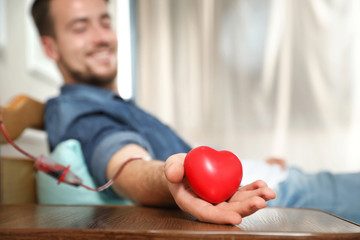 Young man making blood donation in hospital, focus on hand