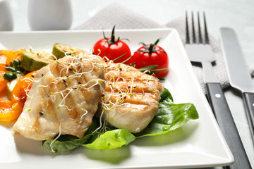 Tasty grilled fish with garnish on table, closeup