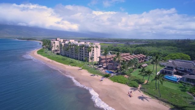 Flying low along the coast of Kihei, Hawaii on a sunny day, panning to the left