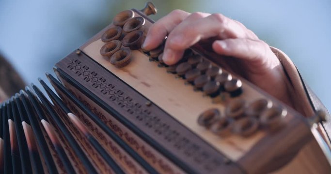 Close up slow motion shot, musician in traditional music costume playing wooden accordion, 4K.
