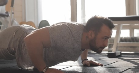 Man exercising in a gym making push-ups on a floor and clap hands