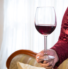glass of red wine held by a woman's hand on white background
