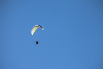 a man paragliding solo on the blue sky over the Dolomites in Italy in a sunny day