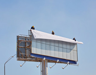 Worker prepares billboard to installing new advertisement.