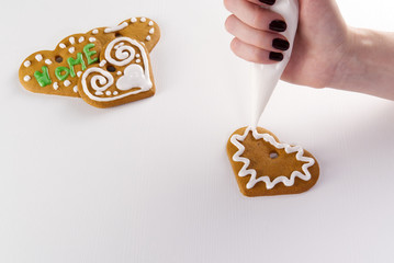 female hand draws white icing on gingerbread cookies. copy space