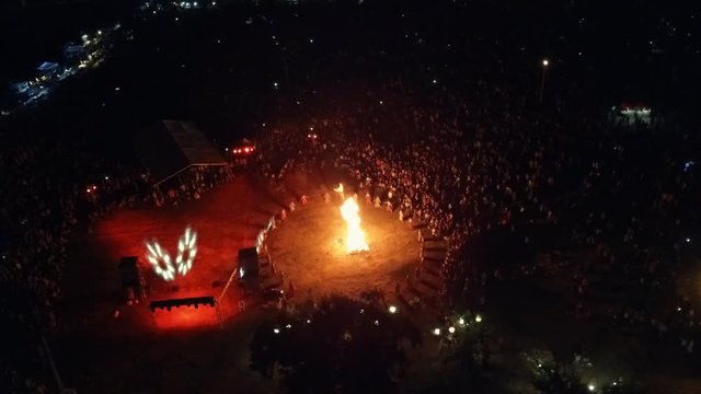 Lots of people crowd celebrate. Ethnic festival holiday with big bonfire. Folk feast concert in the countryside in a rural night landscape. Aerial survey 