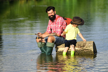 Father and boy son fishing together. His enjoys talking to father. Concept of a retirement age. Happy father and son fishing in river holding fishing rods.