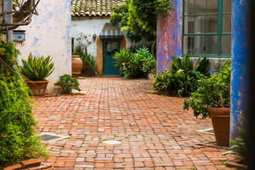 Fototapeta na wymiar Picturesque garden courtyard with potted plants and enclosed by rustic plaster walls in vibrant hues of purple, pink, and blue