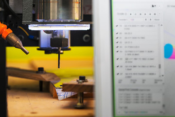 A CNC machine cutting shapes out of an acrylic sheet of plastic, using a computer to send commands...