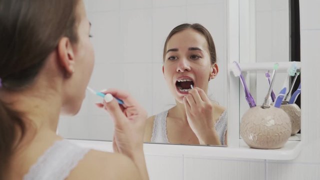 Oral hygiene with metal braces. Brushes teeth with toothbrush and toothpaste. Close-up.