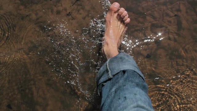 Mans foot walking on the river. High angle.